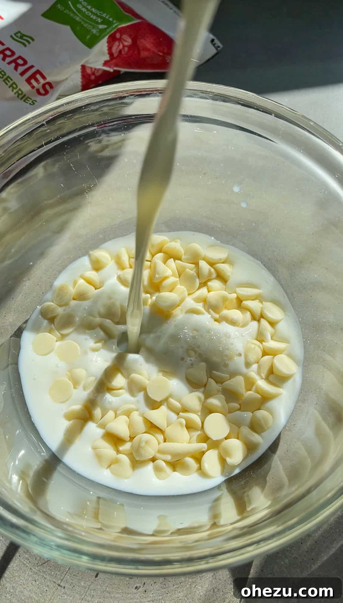 Pouring hot milk over white chocolate chips in a bowl to create the smoothie base.