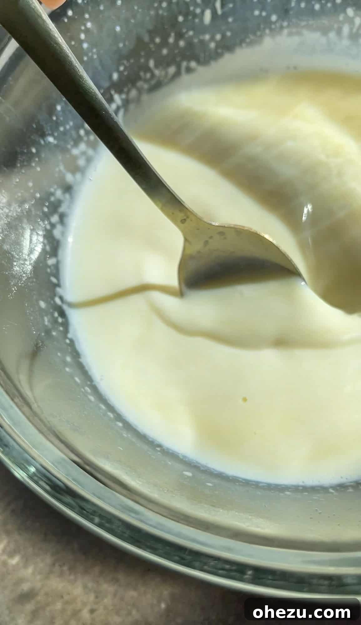Stirring melted white chocolate into warm milk until fully combined, creating a creamy base.