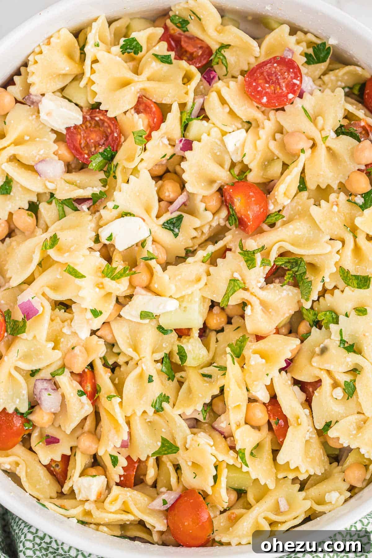 A close-up overhead shot of the finished chickpea pasta salad in a large serving bowl