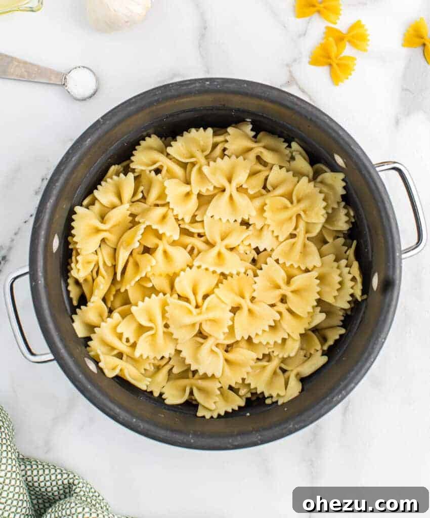 Cooked bowtie pasta draining in a colander in the sink
