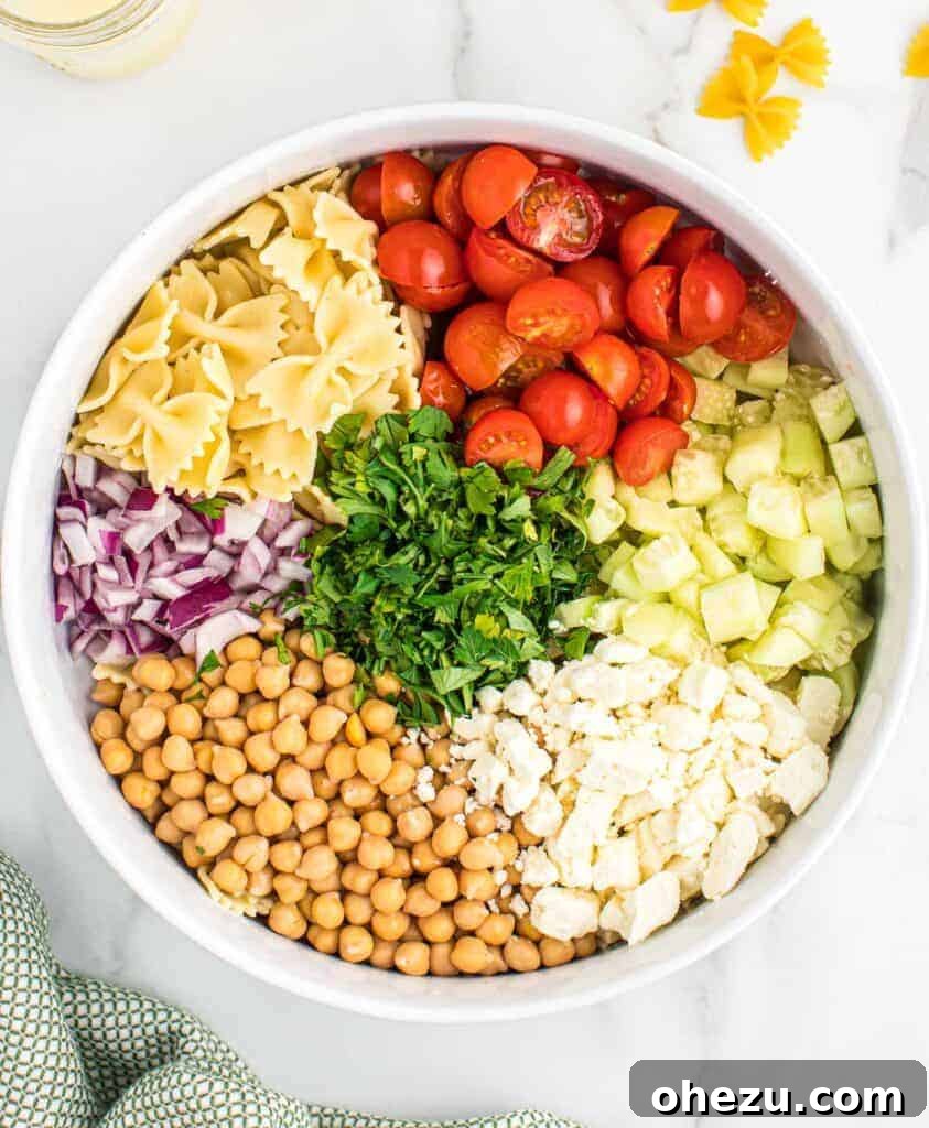 Prepared ingredients for pasta salad, including diced vegetables and chickpeas, in a bowl