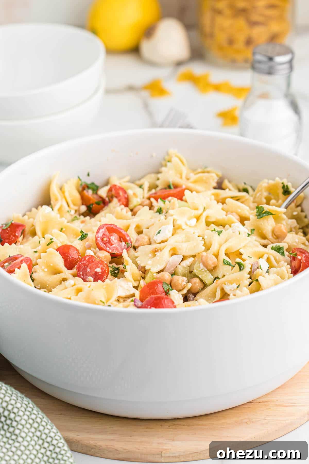 A large bowl of chickpea pasta salad on a wooden table, ready for a gathering
