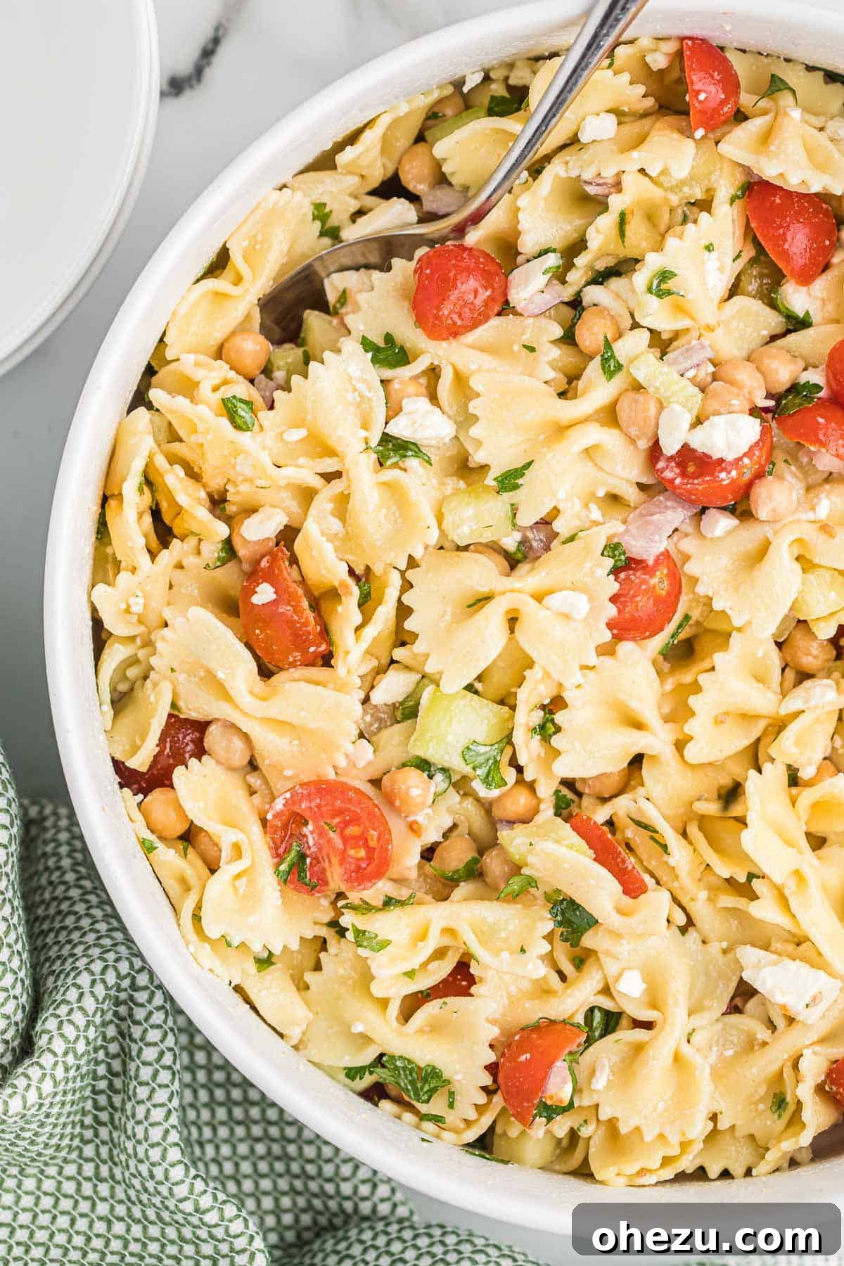 A vibrant bowl of chickpea pasta salad, garnished with fresh parsley, ready to eat