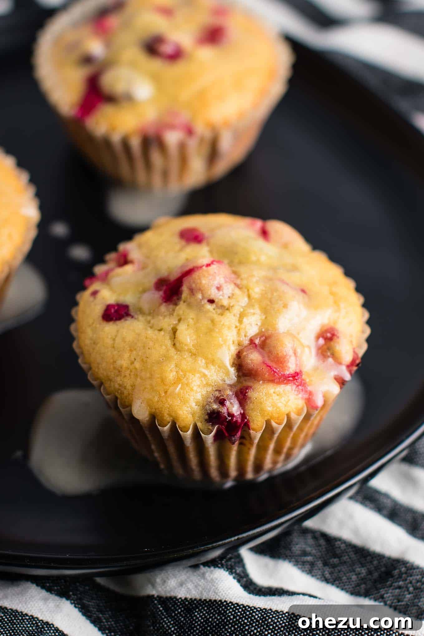 A single healthy Cranberry Orange Muffin with a drizzle of orange glaze on a small plate.