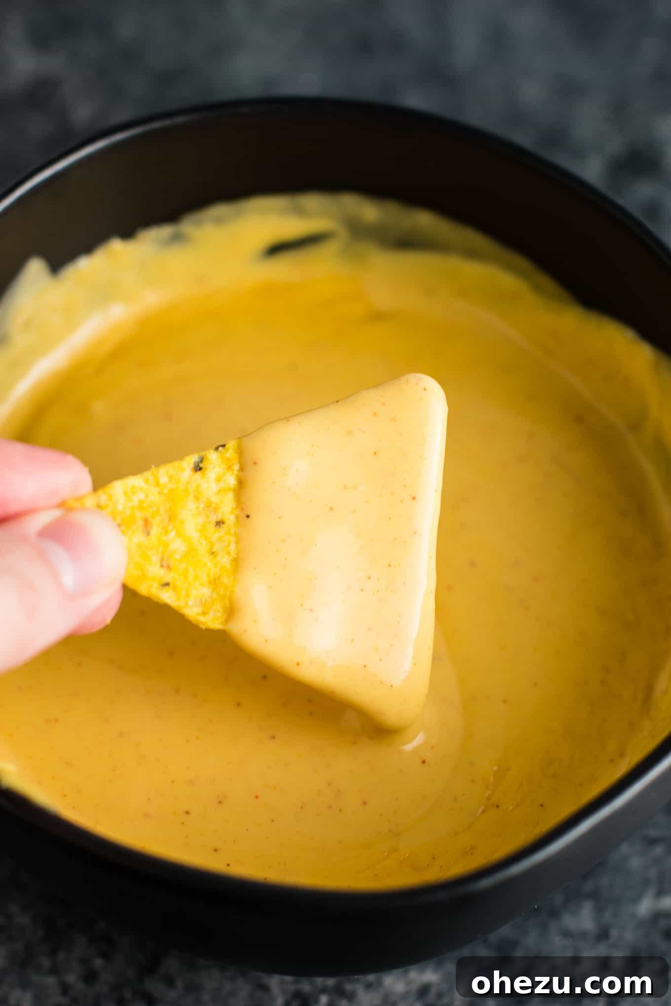 5-Minute Creamy Nacho Cheese Dip 18 A beautiful overhead shot of a finished bowl of the best easy homemade nacho cheese sauce, presented on a wooden board.