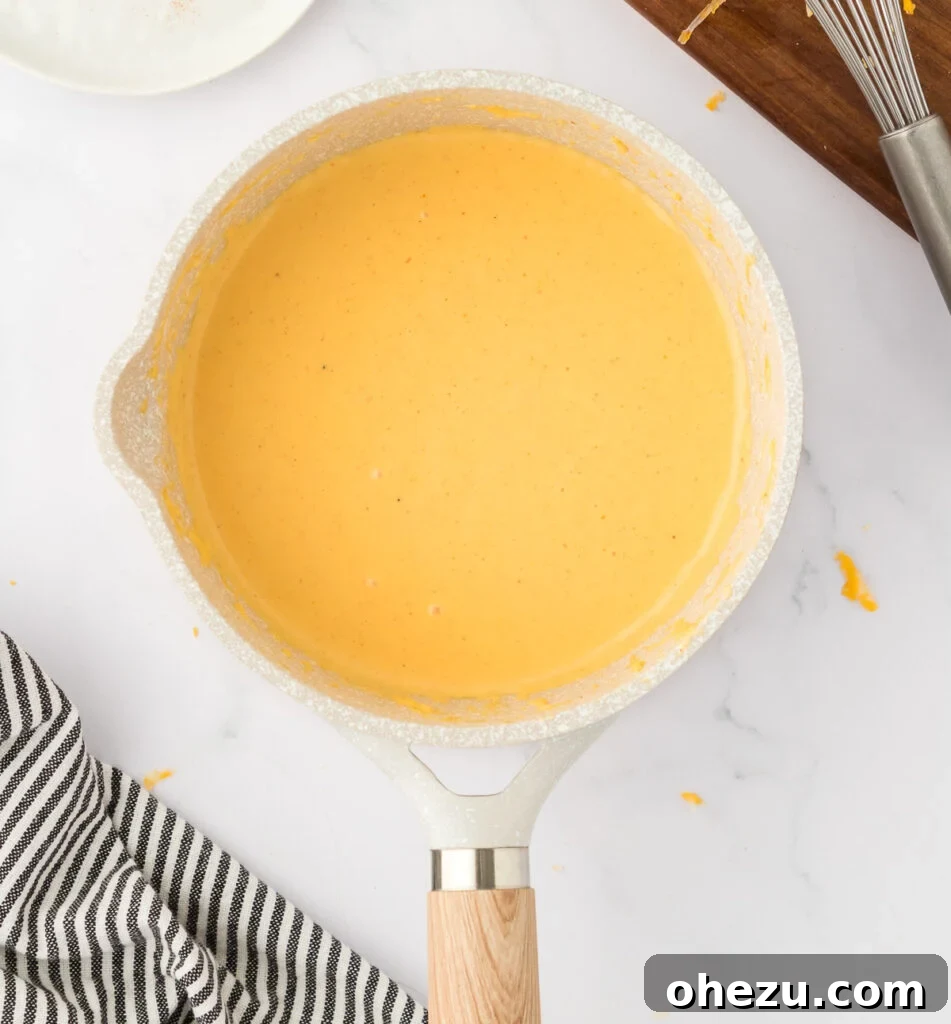 5-Minute Creamy Nacho Cheese Dip 8 A close-up of a pan filled with beautifully smooth, thick, and creamy 5-minute nacho cheese sauce, ready to be served.