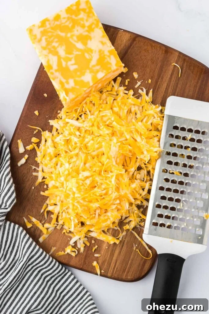 5-Minute Creamy Nacho Cheese Dip 9 A generous pile of freshly shredded Colby Jack cheese resting on a dark wooden cutting board, ready for immediate use.