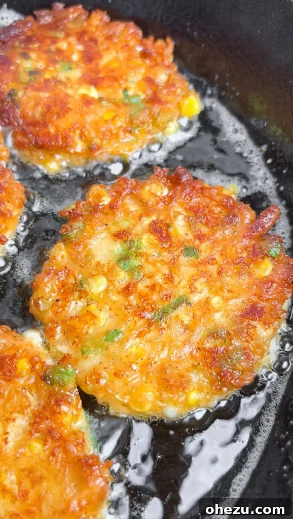 A perfectly plated stack of Cheesy Corn Fritters with a side of creamy herb aioli.
