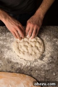 Naples' Authentic Pizza Masterpiece 12 A hand gently pressing down on pizza dough, leaving the crust untouched