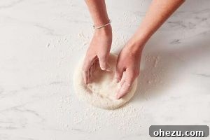 Naples' Authentic Pizza Masterpiece 13 Hands stretching pizza dough into a circular shape
