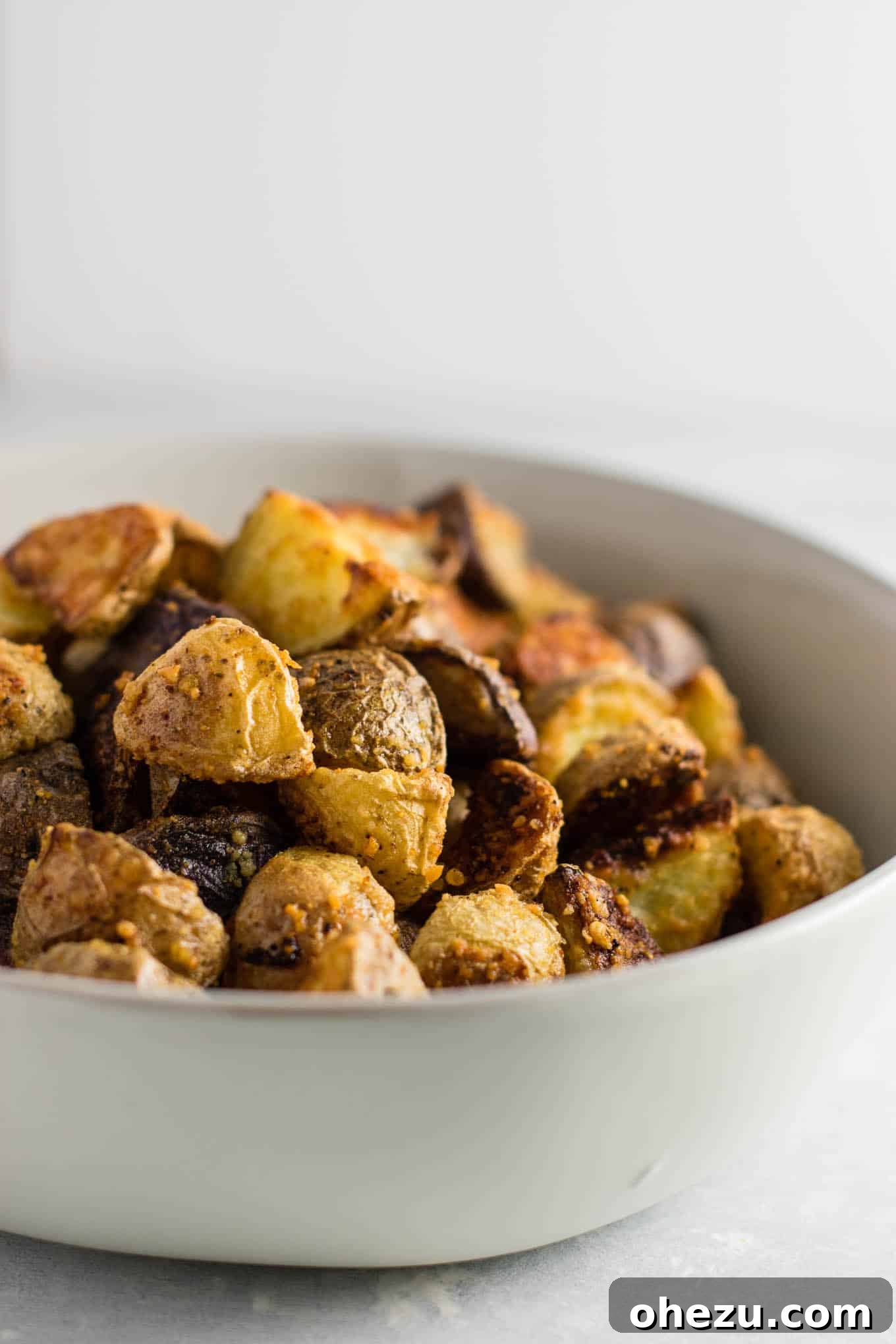 A generous serving of crispy garlic parmesan roasted potatoes in a bowl, perfect for a family meal.
