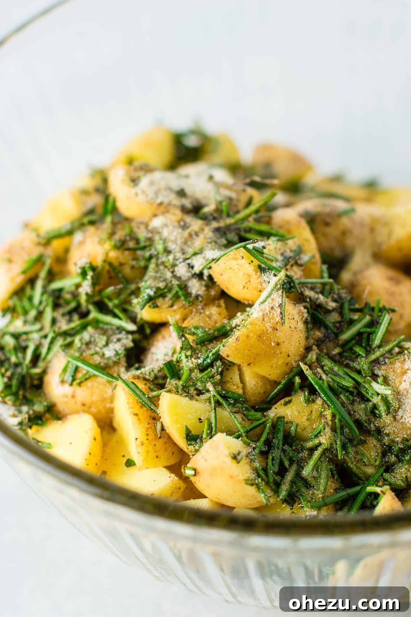 The seasoned and oiled potatoes spread out in a single layer on a baking sheet, ready to be placed into the hot oven for roasting.