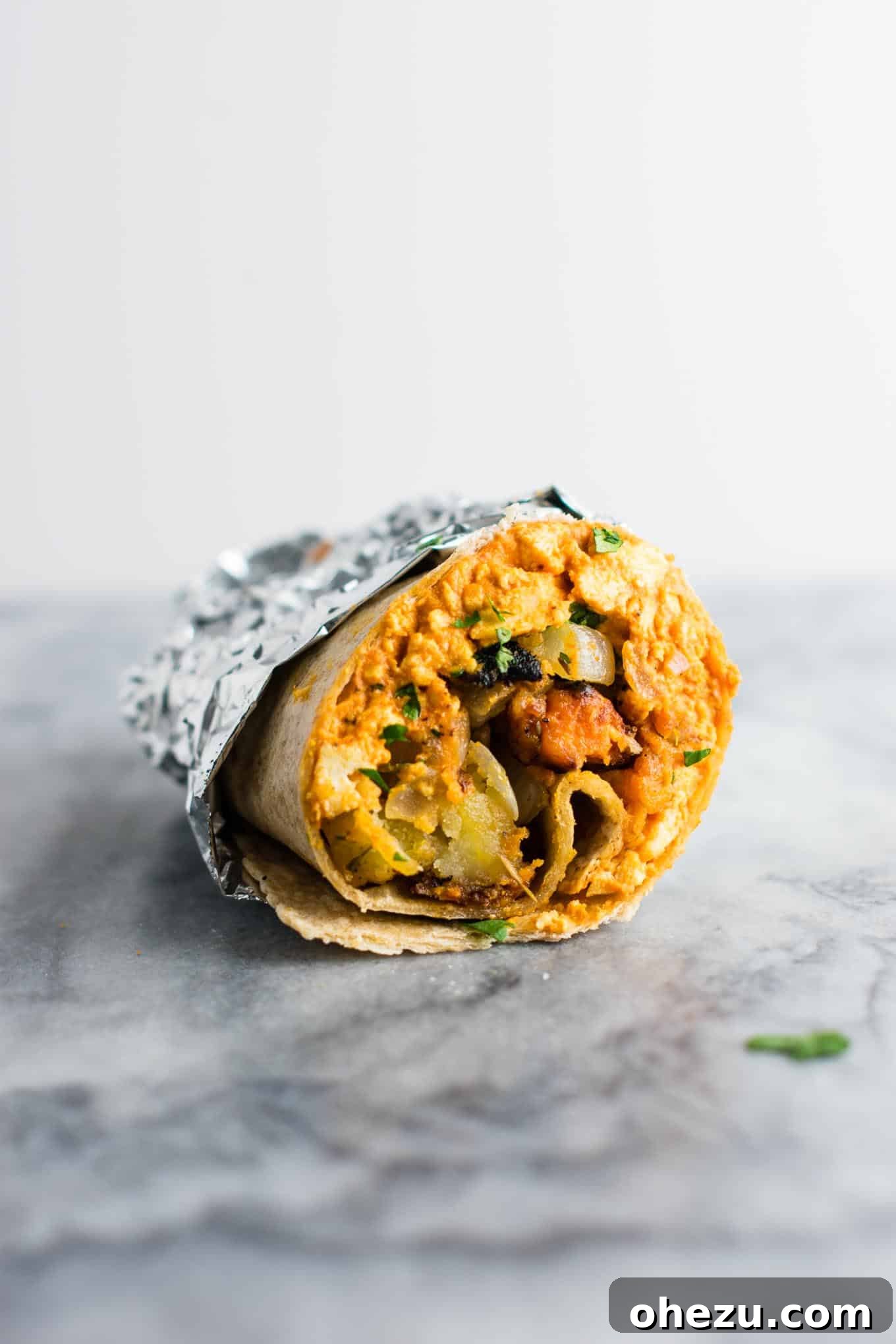 A fresh, hot vegan breakfast burrito on a plate, ready to be enjoyed