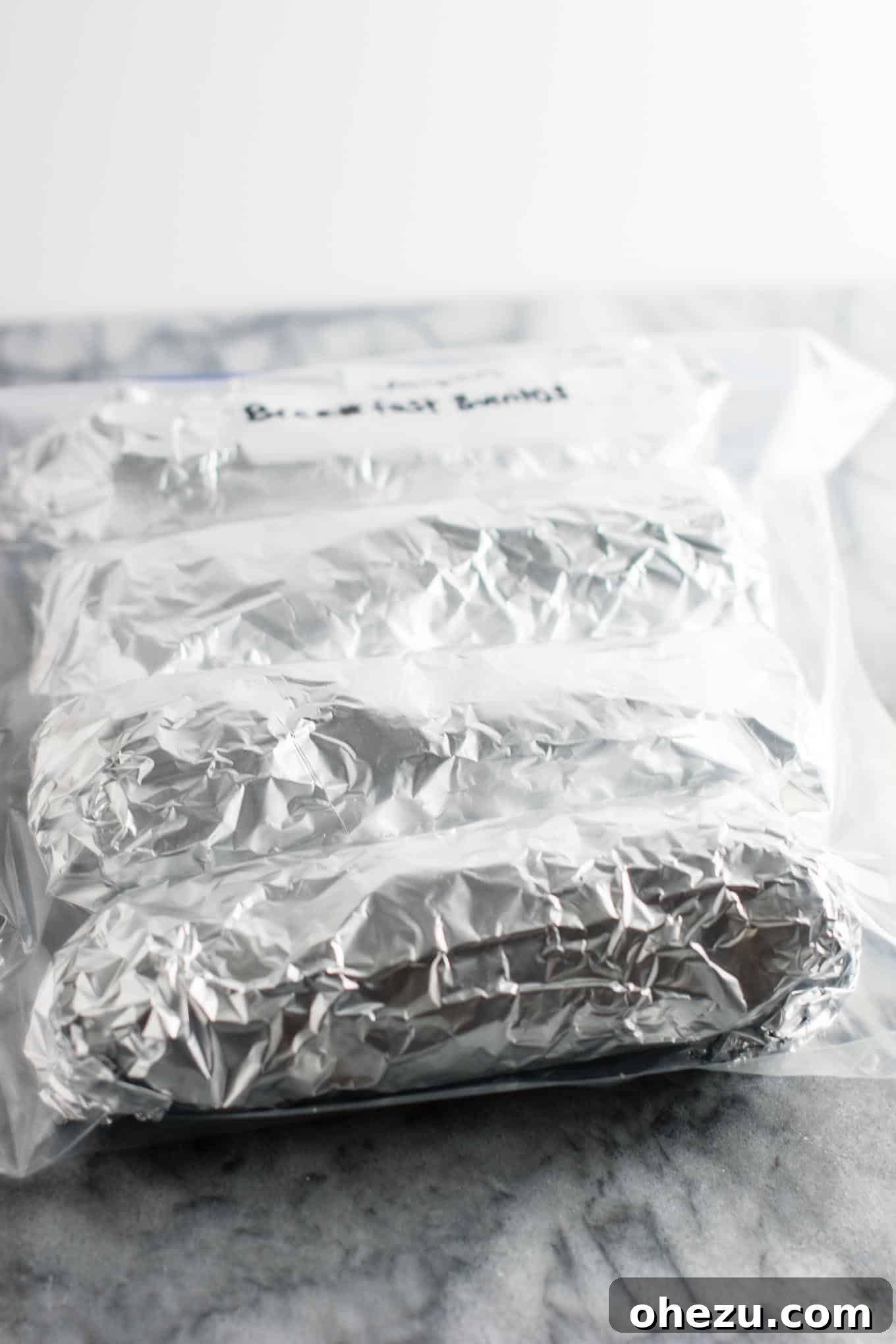 Frozen vegan breakfast burritos, individually wrapped in foil and stacked