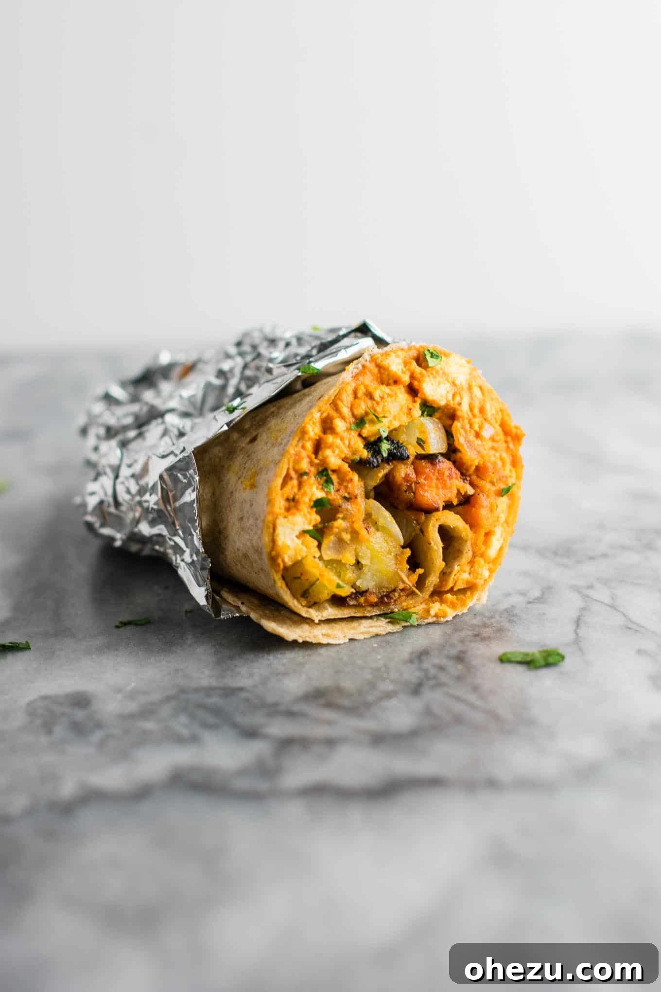 A beautifully assembled vegan breakfast burrito showcasing the scrambled tofu and crispy hash filling