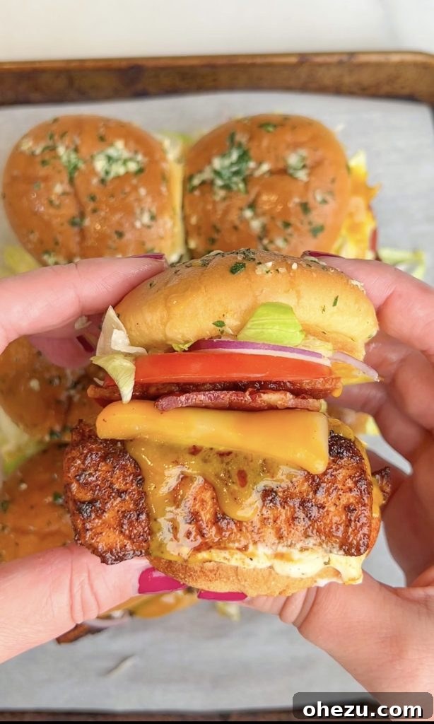 Zesty Honey Mustard Blackened Salmon BLT Sliders 4 Fully assembled Blackened Salmon BLT Sliders showing layers of salmon, bacon, cheese, and vegetables