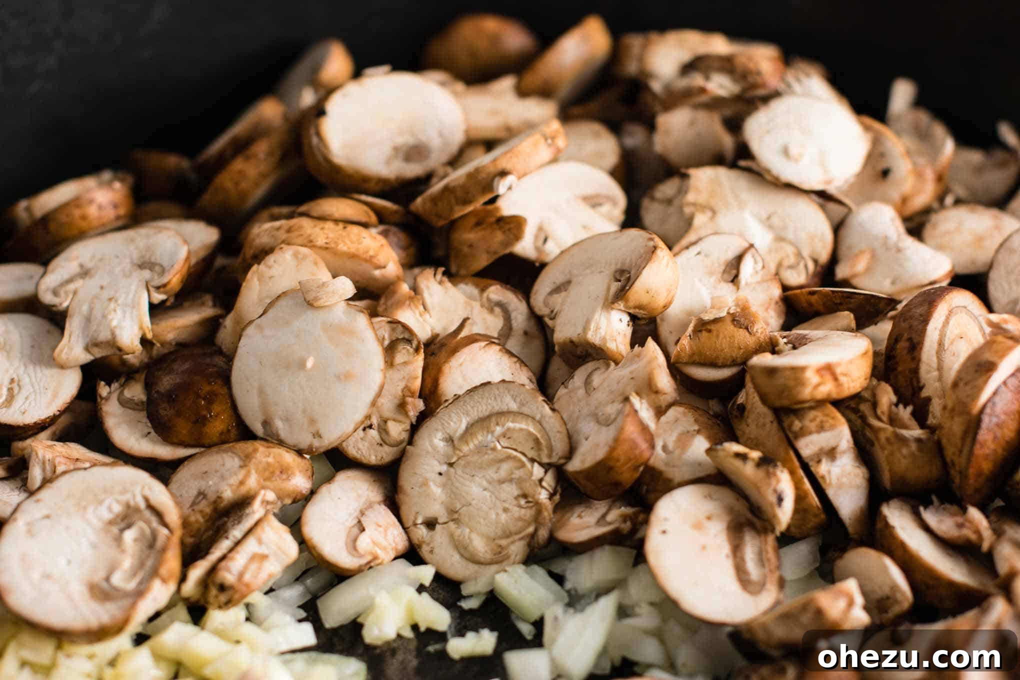 A close-up view of freshly sliced baby bella mushrooms, showcasing their delicate texture and readiness for cooking.