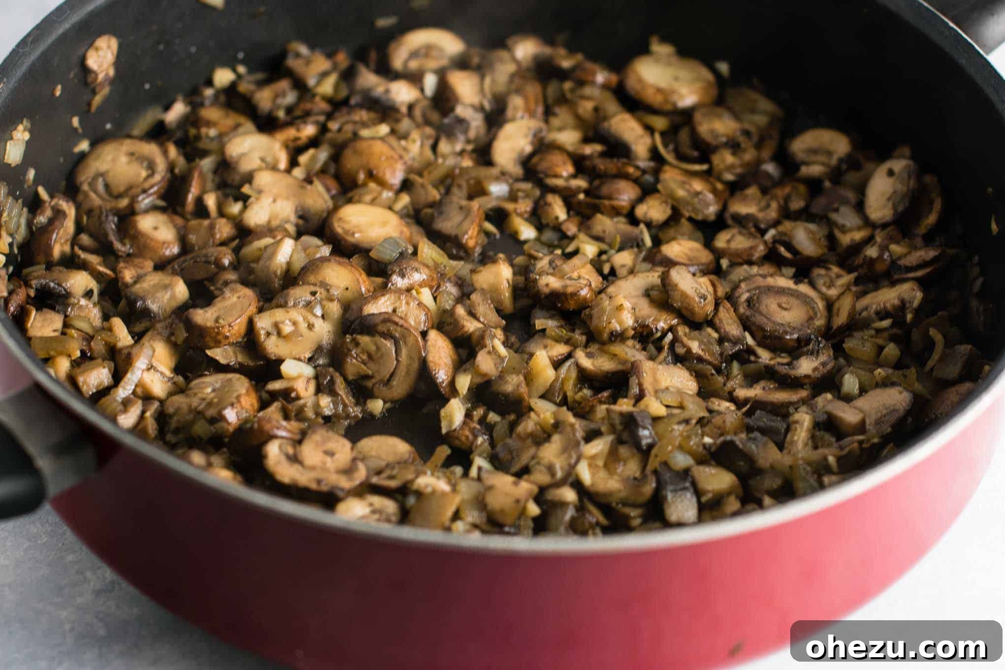 The savory mixture of mushrooms, garlic, and onion expertly cooked down in a skillet, displaying a rich brown color and tender texture, indicating they are perfectly caramelized and ready for the next step.