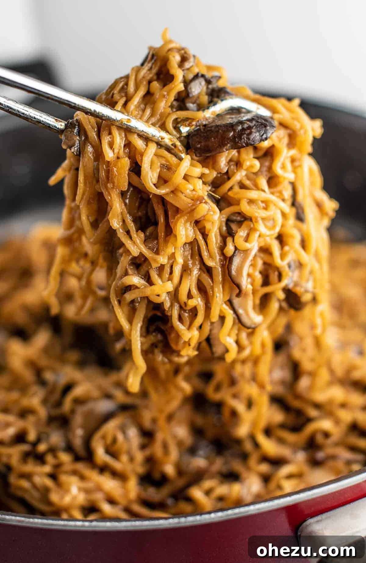 Gourmet Stir Fry Sauce 8 Ramen noodles with mushrooms being pulled with tongs from a hot pan, demonstrating perfect stir fry texture