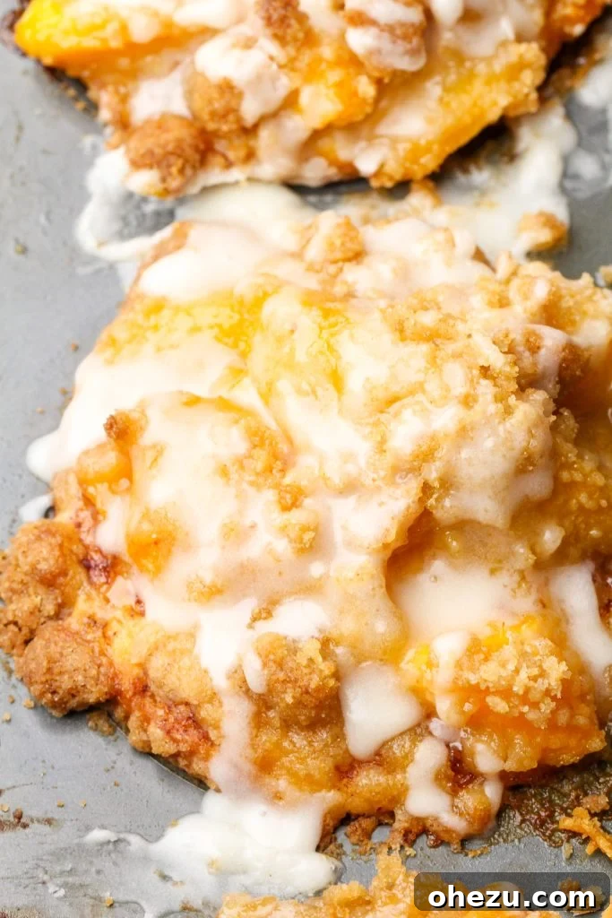Close-up of baked peach cobbler cinnamon rolls with streusel topping, ready to serve