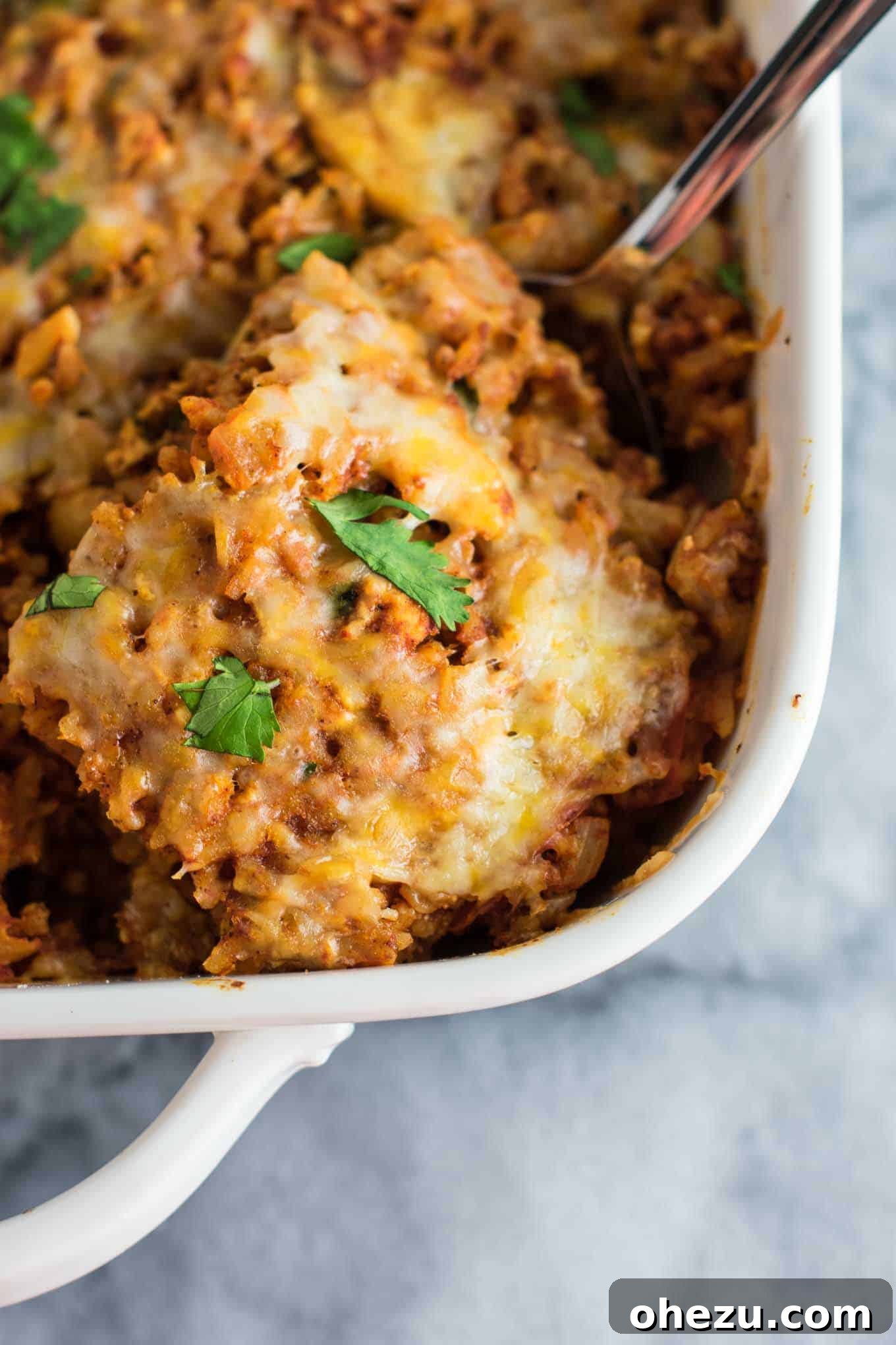 Hearty Tofu Mexican Rice Bake 12 Close-up of the Tofu Mexican Rice Casserole with a spoon scooping out a portion, highlighting the rich and chunky texture of the dish, ready for serving.