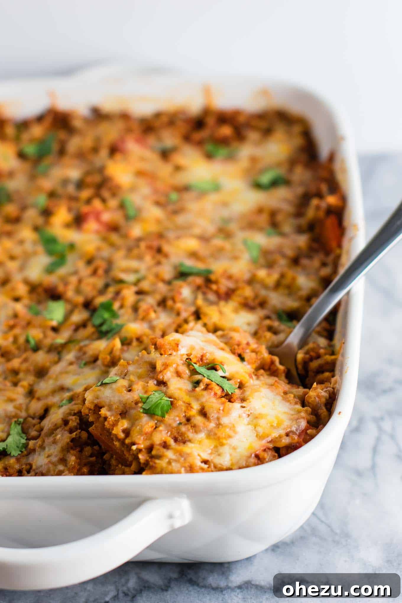Hearty Tofu Mexican Rice Bake 4 A large baking dish filled with the colorful Tofu Mexican Rice Casserole mixture before baking, showcasing bell peppers, mushrooms, rice, and tofu. This vegetarian dish is vibrant and full of wholesome ingredients.