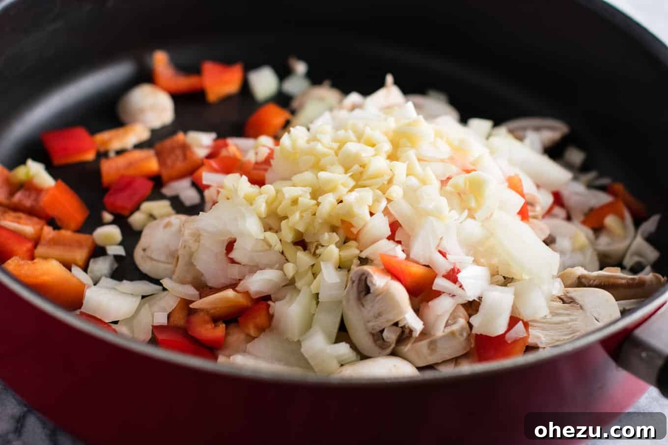 Hearty Tofu Mexican Rice Bake 5 Ingredients for Tofu Mexican Rice Casserole laid out: diced red bell pepper, sliced mushrooms, chopped onion, and minced garlic ready for sautéing. Emphasizing fresh, wholesome vegetables.