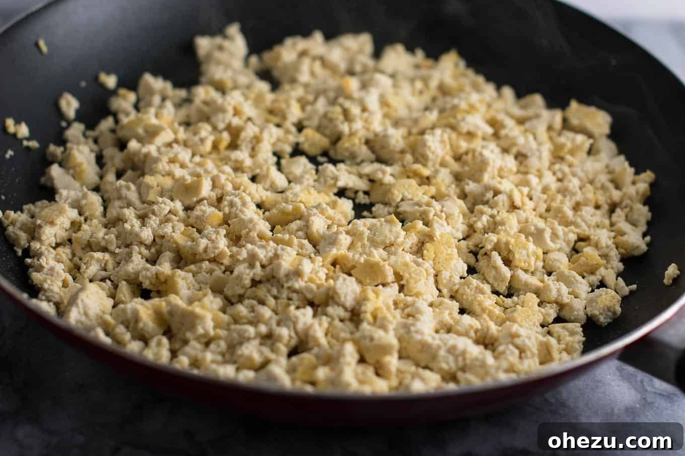Hearty Tofu Mexican Rice Bake 6 Skillet with scrambled extra-firm tofu being cooked, showing its resemblance to scrambled eggs with slightly browned edges. This technique ensures a great texture for the Tofu Mexican Rice Casserole.