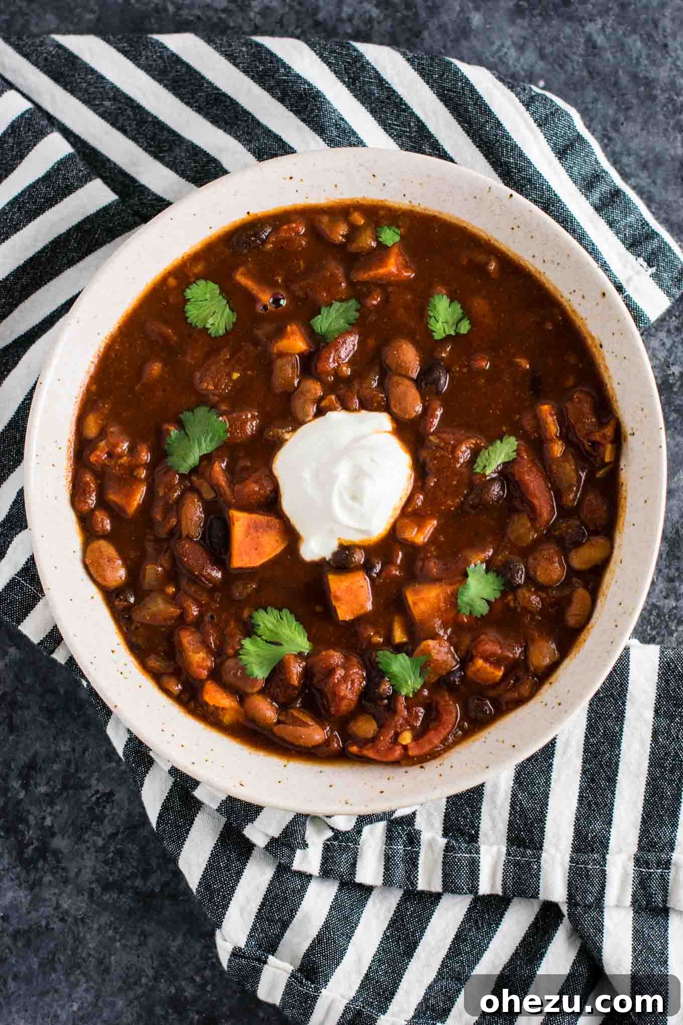 Effortless Plant-Based Sweet Potato Chili in Your Slow Cooker 2 A vibrant bowl of Slow Cooker Vegetarian Sweet Potato Chili, garnished with fresh cilantro and a dollop of sour cream, showcasing its rich texture and color. Perfect for a hearty, meatless dinner.