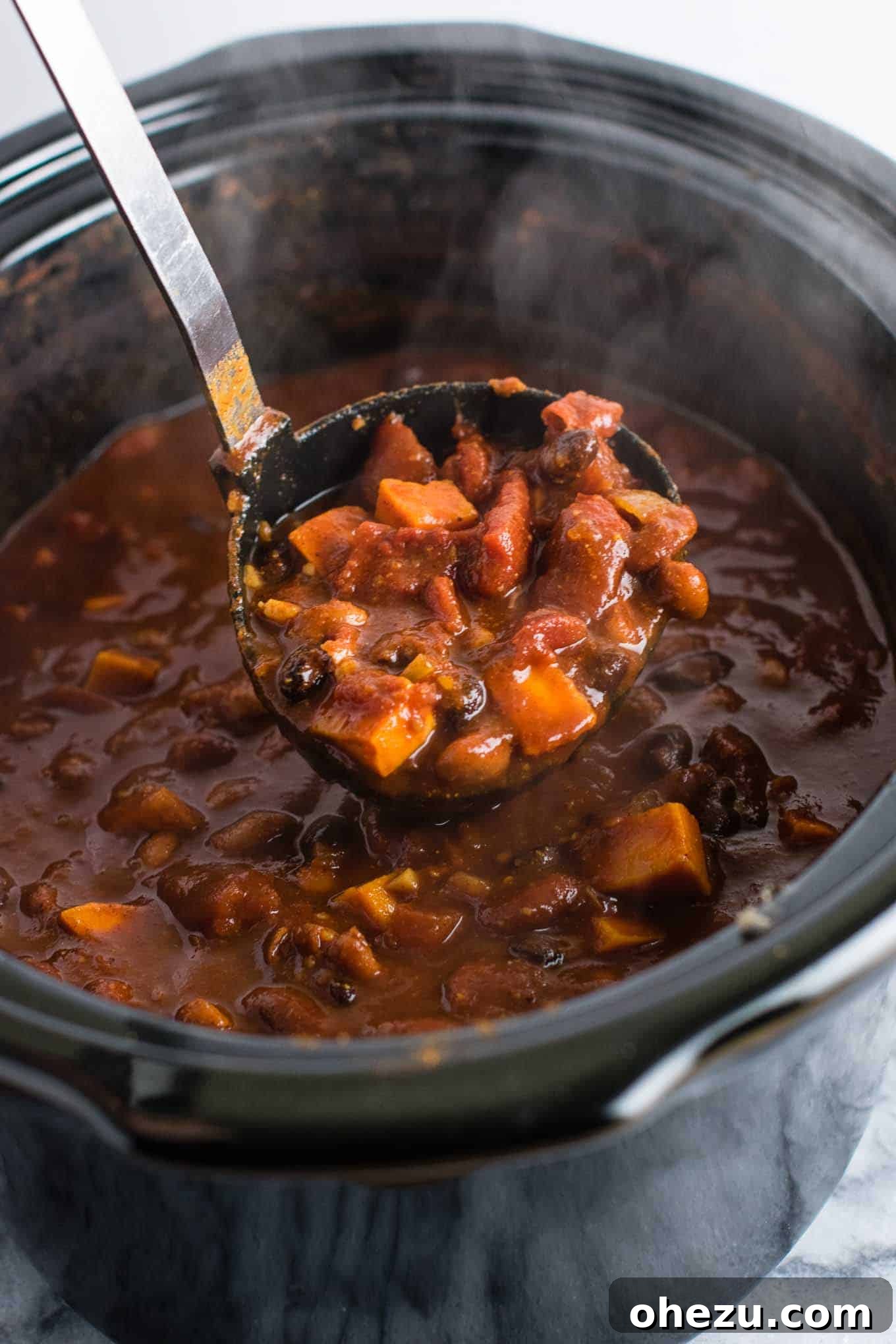 Effortless Plant-Based Sweet Potato Chili in Your Slow Cooker 3 A close-up of a slow cooker filled with uncooked ingredients for vegetarian sweet potato chili, including diced sweet potatoes, beans, and tomatoes, ready to be cooked.