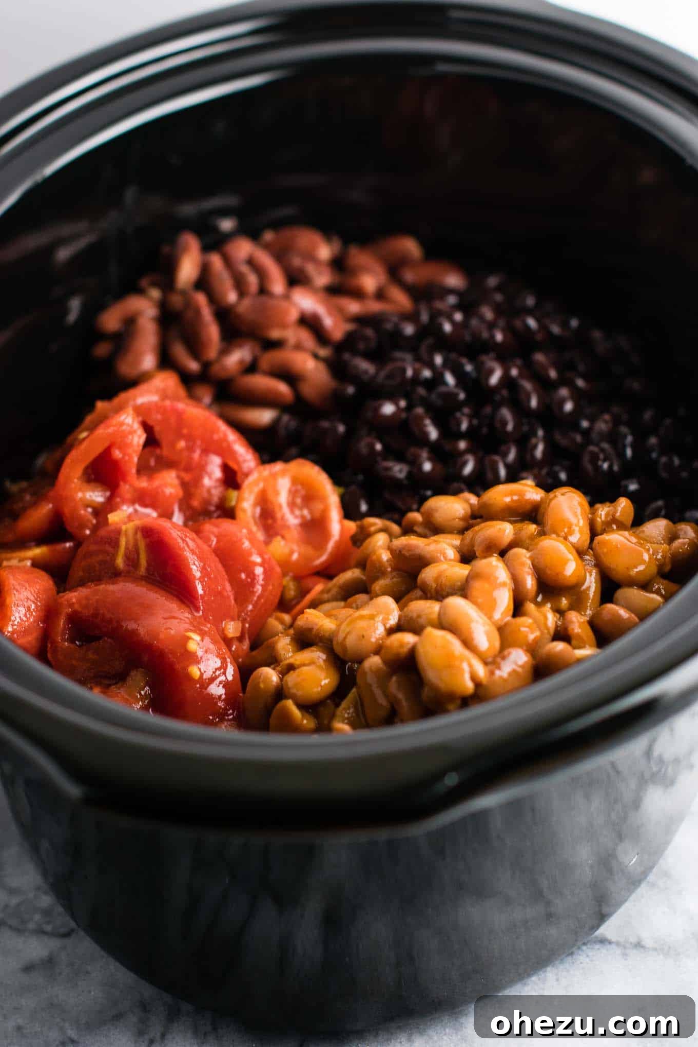 Effortless Plant-Based Sweet Potato Chili in Your Slow Cooker 5 Various canned ingredients for chili including kidney beans, black beans, chili beans, diced tomatoes, and stewed tomatoes, next to fresh spices.