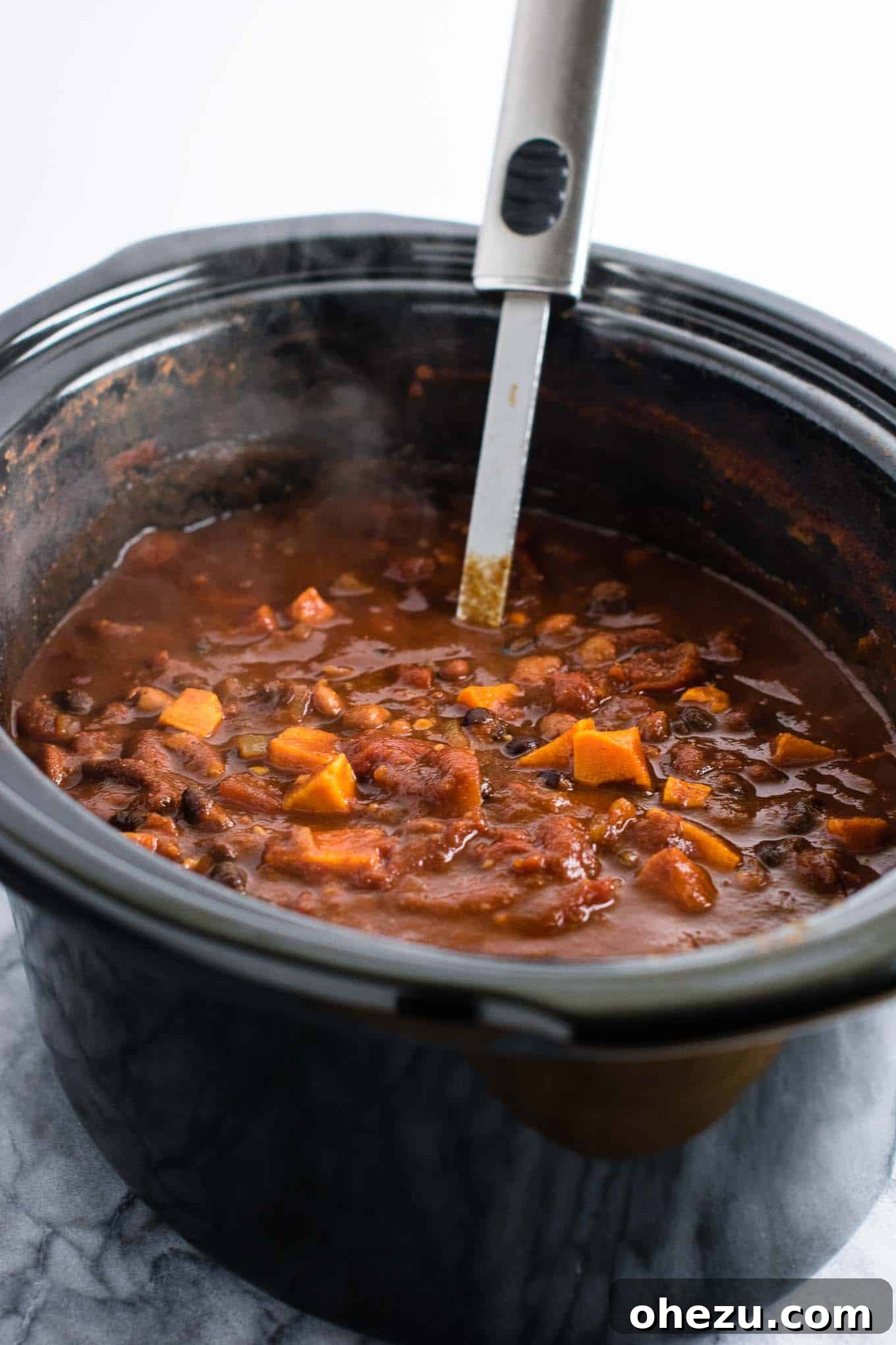 Effortless Plant-Based Sweet Potato Chili in Your Slow Cooker 6 The slow cooker filled with all the ingredients for vegetarian sweet potato chili, including colorful beans, tomatoes, sweet potatoes, and spices, before cooking.