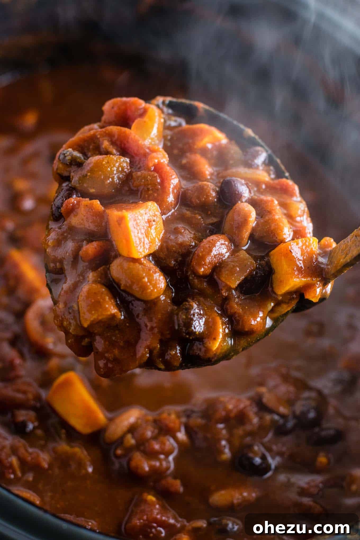 Effortless Plant-Based Sweet Potato Chili in Your Slow Cooker 8 A bowl of slow cooker vegetarian sweet potato chili topped generously with sour cream, shredded Mexican cheese, fresh cilantro, and a lime wedge, ready to be enjoyed.