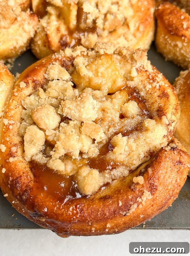 Various ingredients for apple pie cinnamon rolls including apples, butter, sugar, and cinnamon, laid out on a wooden surface