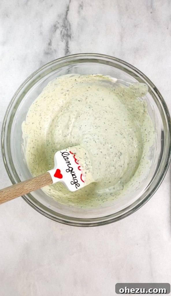 Step-by-step image of mixing the creamy ingredients and shredded chicken for the enchilada dip filling