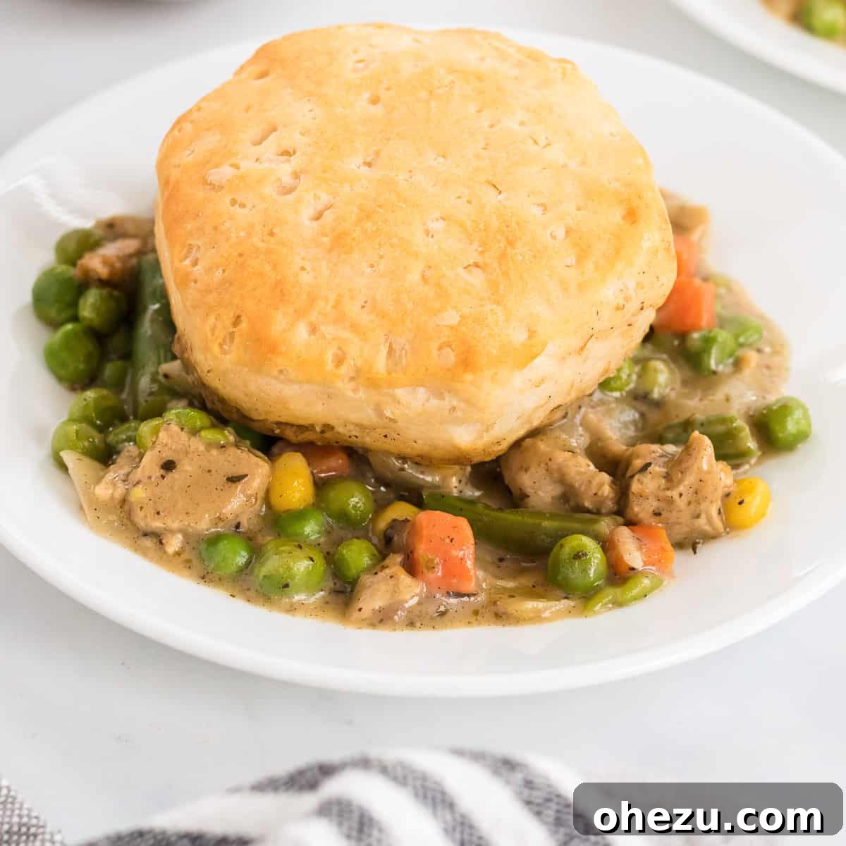 Deconstructed veggie pot pie featuring a single golden biscuit on a rustic plate, highlighting the delicious textures and presentation.