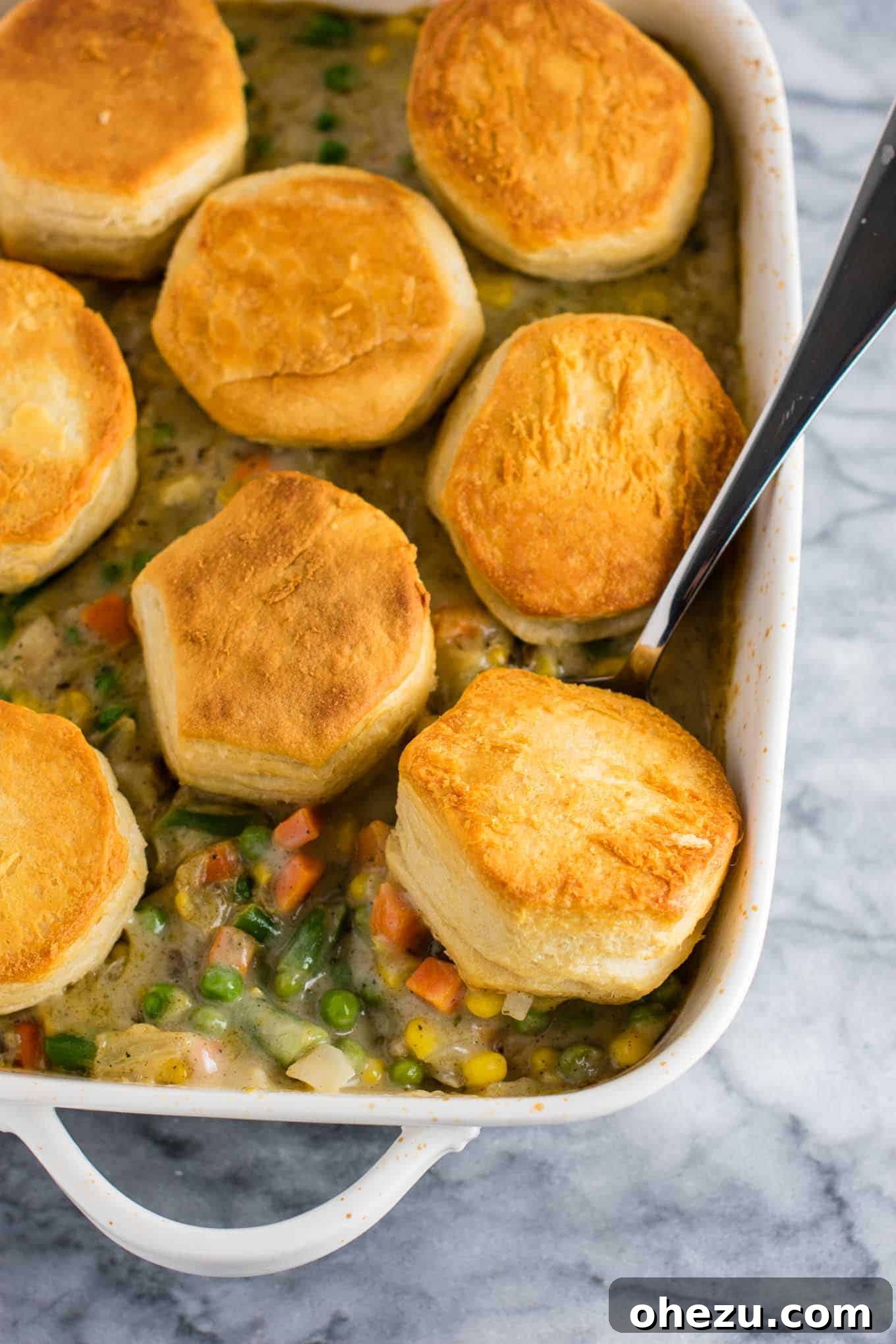Deconstructed Veggie Pot Pie Recipe with flaky golden biscuits on top, served in a casserole dish. A delicious and simple twist on a classic vegetarian comfort food, perfect for a healthy meatless dinner. #veggiepotpie #vegetarian #meatless #dinner #healthydinner