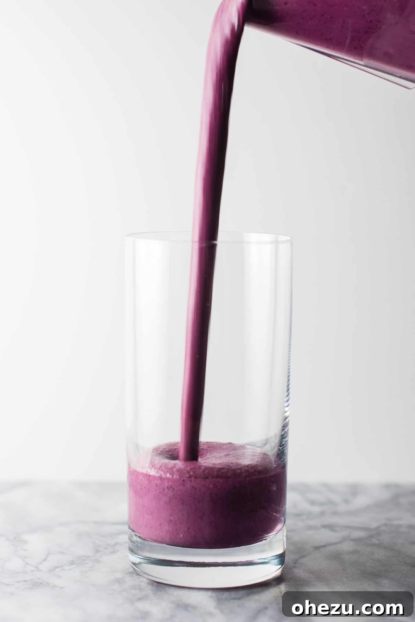 A vibrant, healthy blueberry pie smoothie in a glass, garnished with fresh blueberries and lemon zest. Made with Greek yogurt and rolled oats, it's perfect for breakfast or dessert. #healthy #blueberrysmoothie #blueberrypiesmoothie #vegetarian #greekyogurt #lemonzest #glutenfree