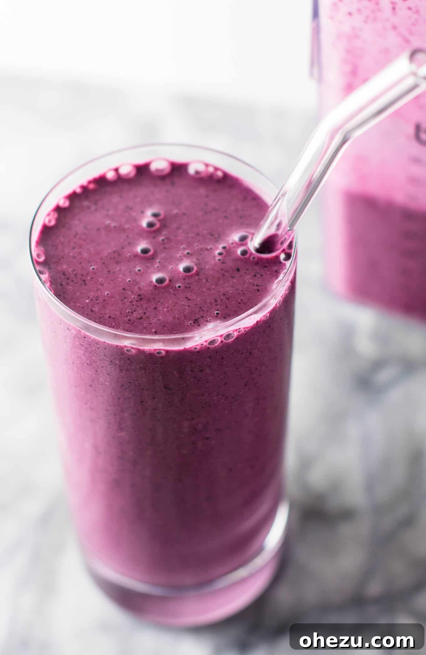 A beautifully composed flat lay of a blueberry pie smoothie glass, fresh blueberries, and a spoon, inviting viewers to try the recipe. Ideal for social media sharing. #healthy #blueberrysmoothie #blueberrypiesmoothie #vegetarian #greekyogurt #lemonzest #glutenfree