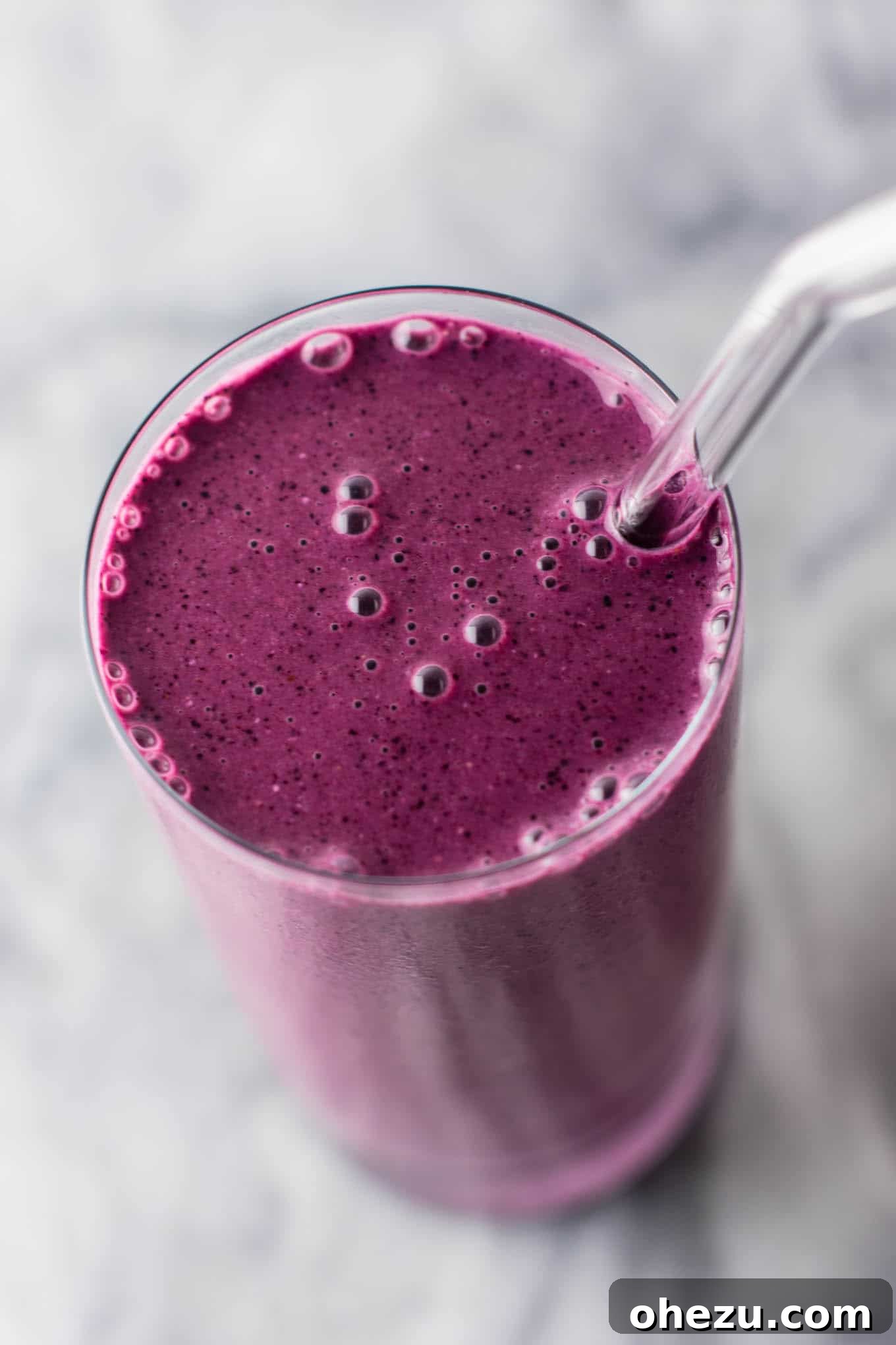 Close-up of a healthy blueberry pie smoothie showing its creamy texture and rich purple color. Features Greek yogurt, rolled oats, and a sprinkle of lemon zest, highlighting its wholesome ingredients. #healthy #blueberrysmoothie #blueberrypiesmoothie #vegetarian #greekyogurt #lemonzest #glutenfree