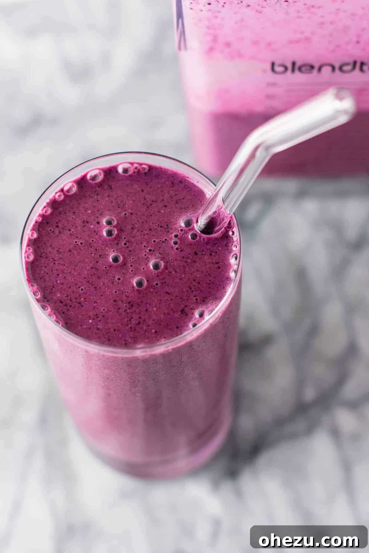 A close-up shot of the blueberry pie smoothie in a glass, with a straw, ready to be enjoyed. The focus is on the texture and the appealing blend of ingredients. #healthy #blueberrysmoothie #blueberrypiesmoothie #vegetarian #greekyogurt #lemonzest #glutenfree