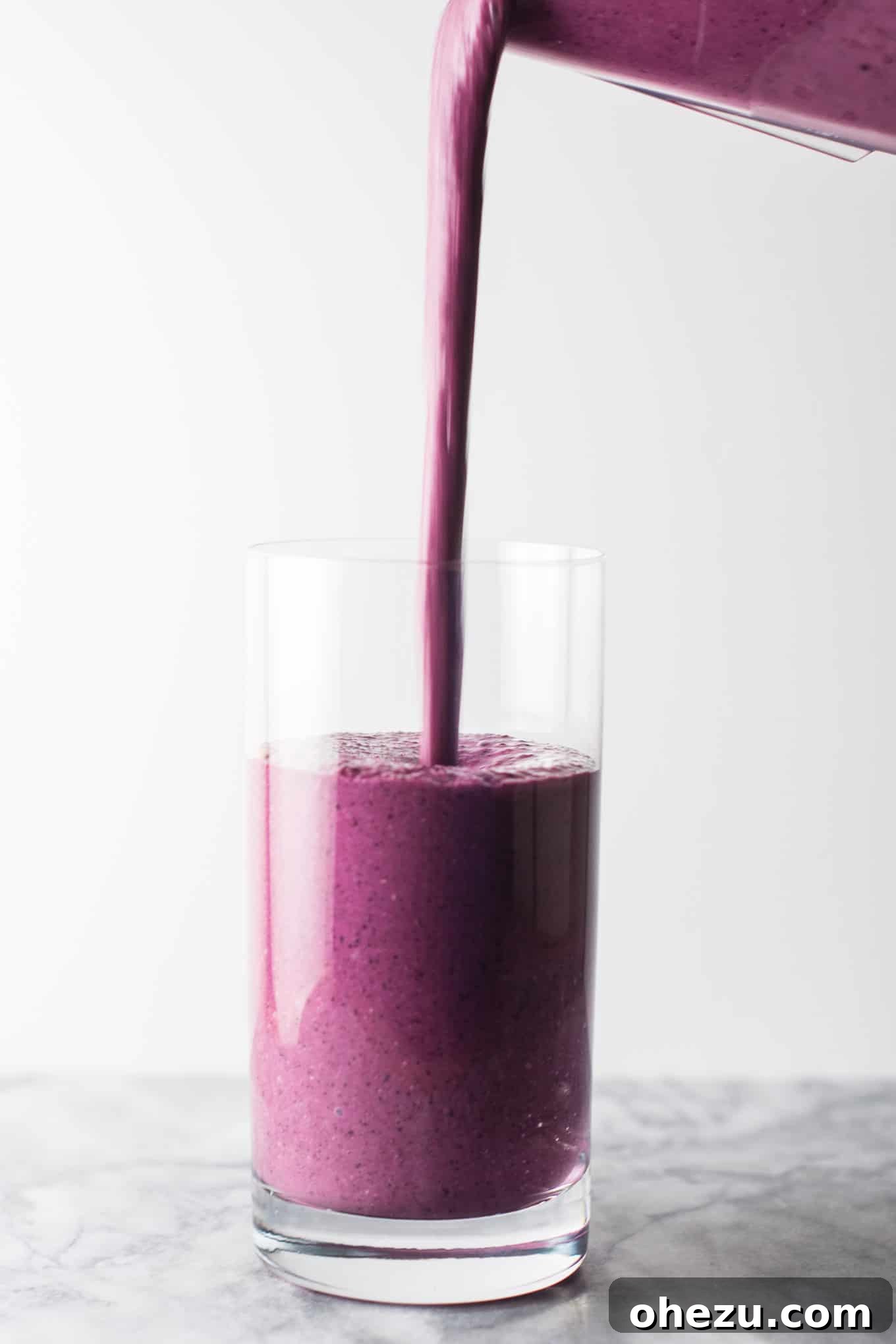 The blueberry pie smoothie poured into a clear glass, showing its smooth and thick consistency, perfect for a satisfying drink. #healthy #blueberrysmoothie #blueberrypiesmoothie #vegetarian #greekyogurt #lemonzest #glutenfree