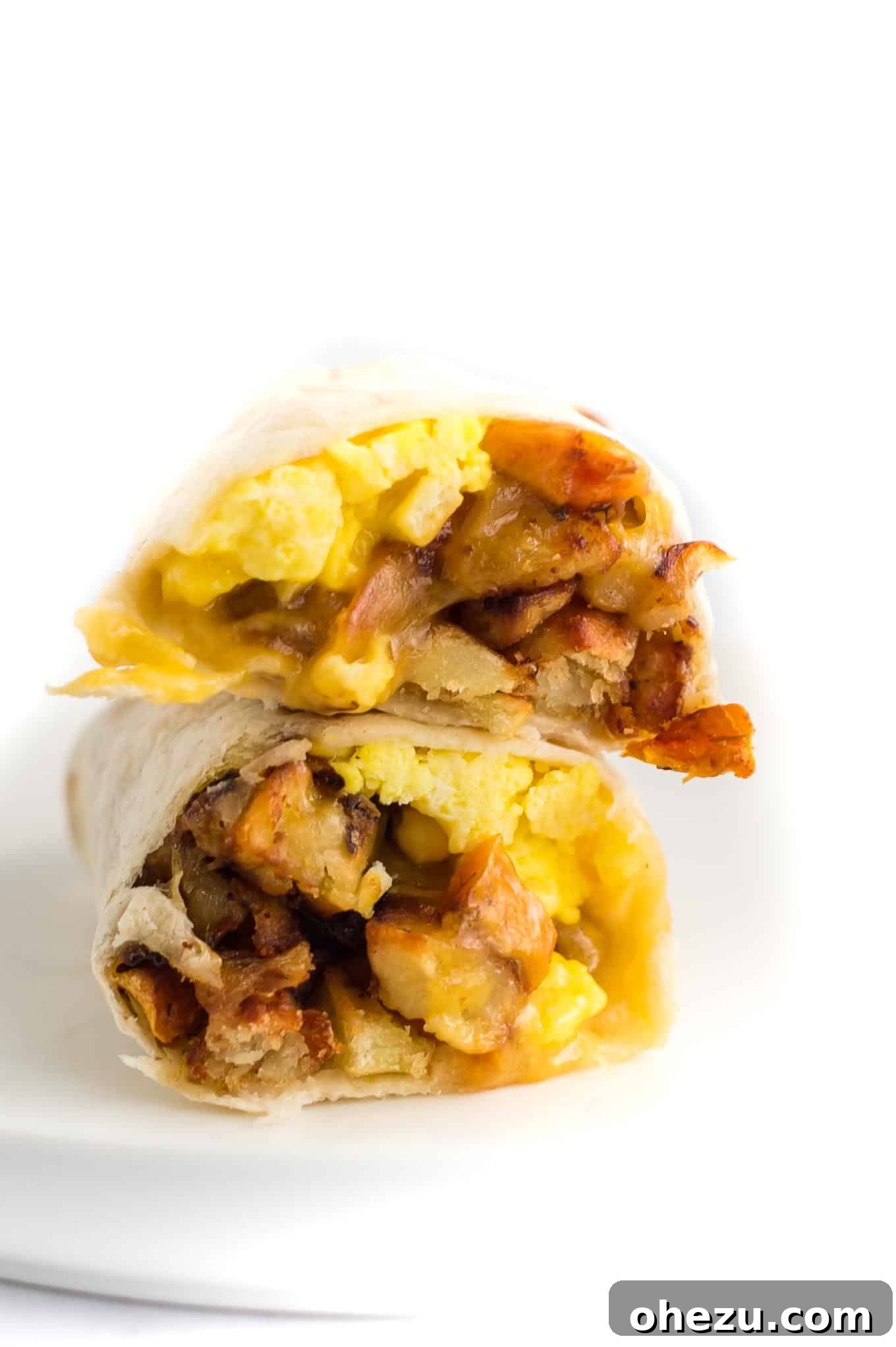 Breakfast Burrito Bliss 8 Two breakfast burritos, artfully cut in half and stacked atop each other, revealing their satisfying and delicious layers.