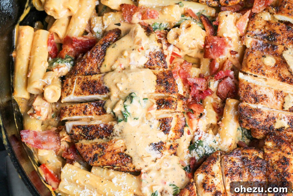 Closeup of Tuscan Chicken Pasta in a skillet, showing creamy sauce, chicken, and spinach