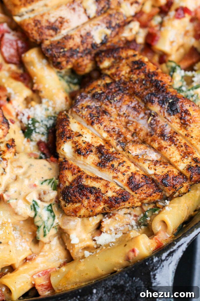 Overhead view of a finished plate of Tuscan Chicken Pasta with fresh basil