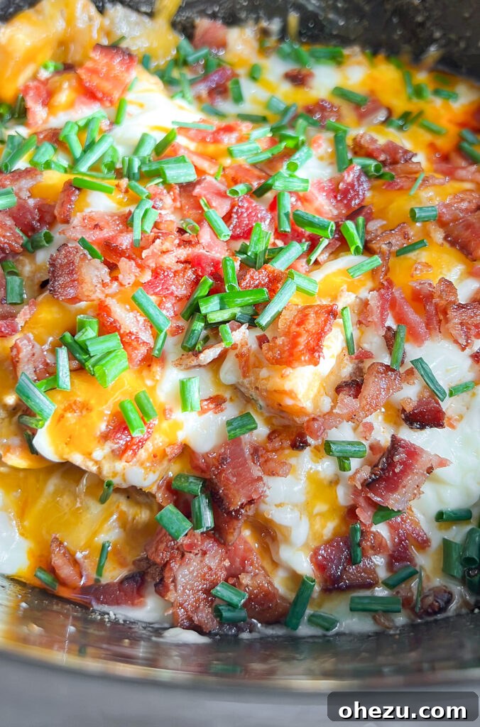 Loaded Slow Cooker Ranch Chicken and Potatoes 2 Cheesy Bacon Ranch Slow Cooker Chicken and Potatoes served in a bowl, garnished with chives and bacon