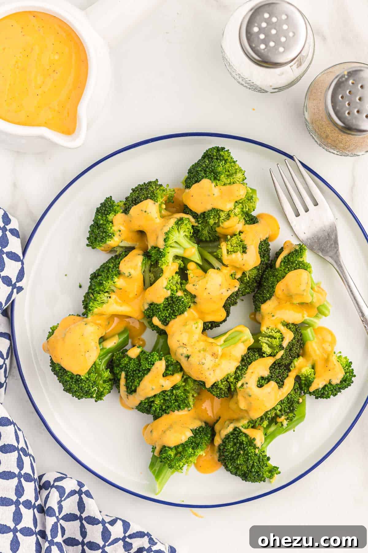 A serving of perfectly steamed broccoli generously coated in a luscious, homemade cheddar cheese sauce, ready for a delicious meal.
