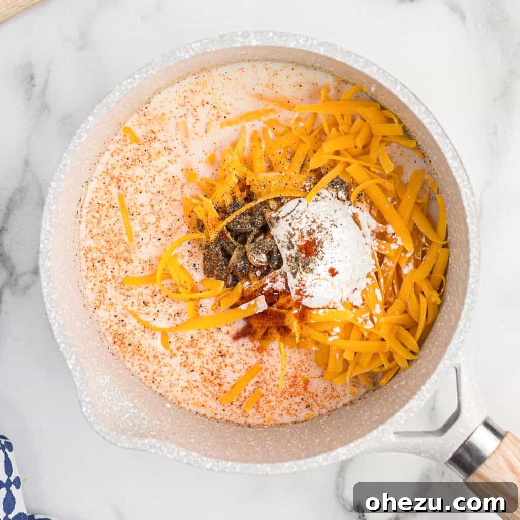 A saucepan filled with milk, cornstarch, and spices, with grated cheddar cheese being added.