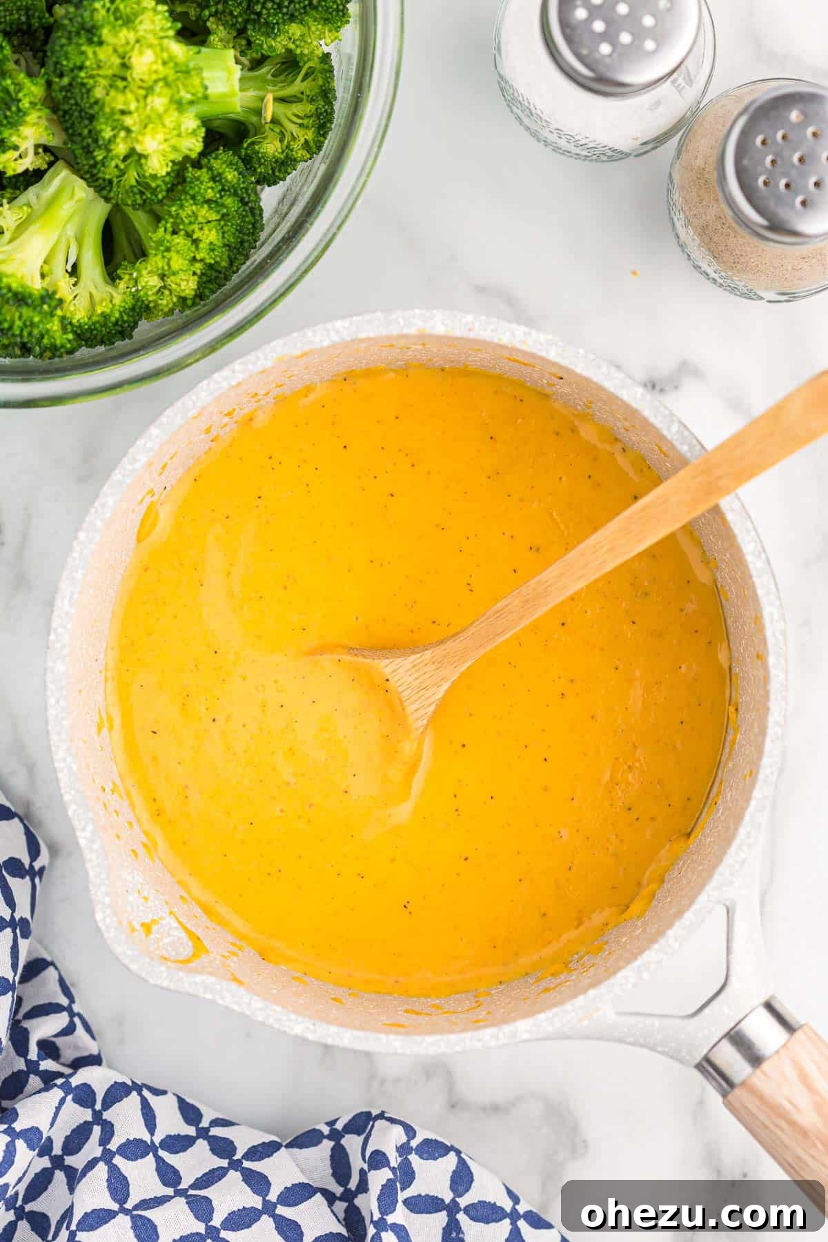 A close-up shot of the creamy cheddar cheese sauce for broccoli simmering gently in a saucepan, ready to be served.