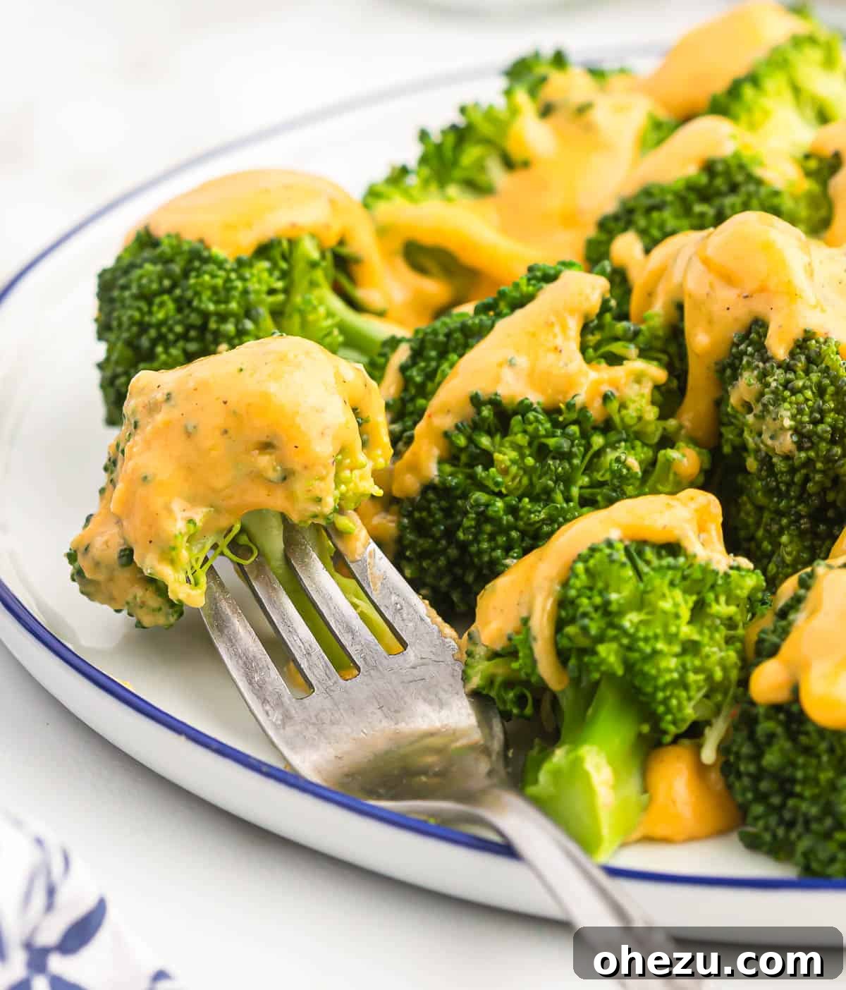 Steamed broccoli florets generously coated with a rich, golden homemade cheese sauce, presented beautifully in a serving dish.